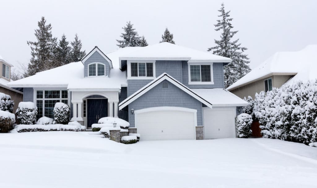 Front view of snow-covered home during rare storm in Pacific Northwest of United States. Homeowners don't have to worry because they have property insurance that covers winter weather.