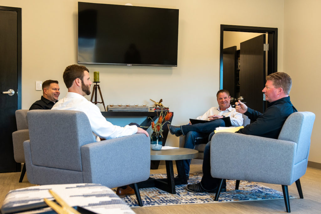 A group of American Safeguard Insurance employees sit together in a circle discussing commercial insurance.