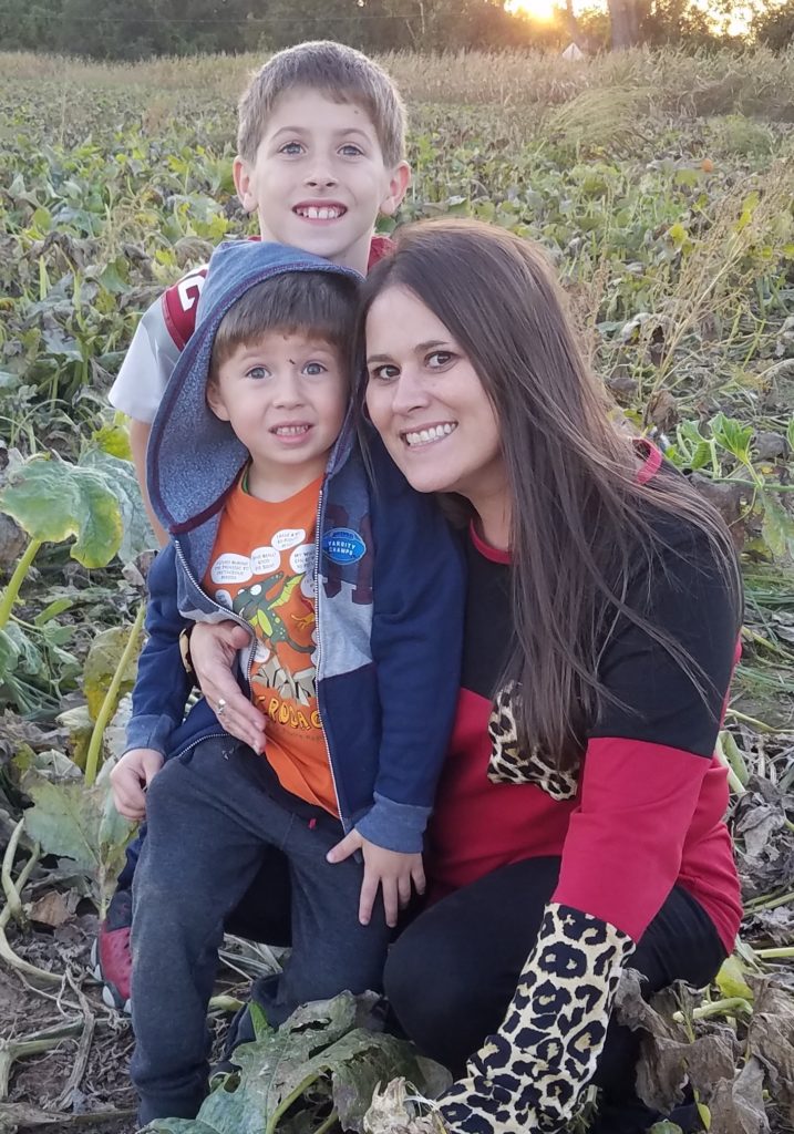 Woman poses with two young boys, smiling at the camera.