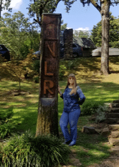Cindy Ellis poses next to wood carving on a fun adventure.