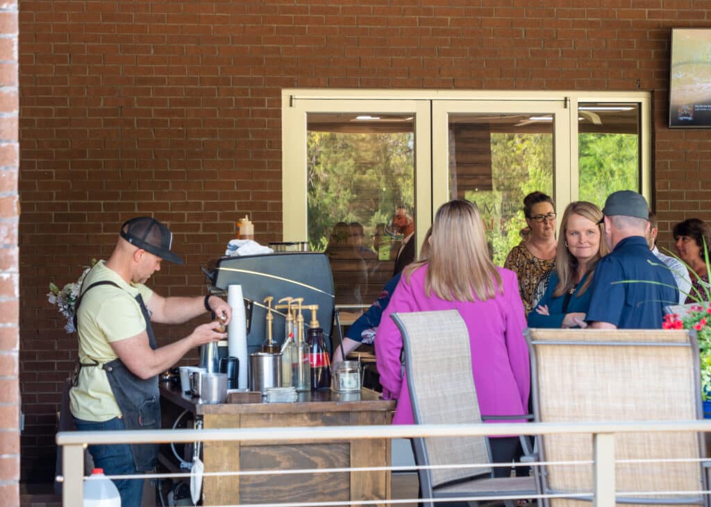 A group of people wait in line at a pop-up coffee shop outside.