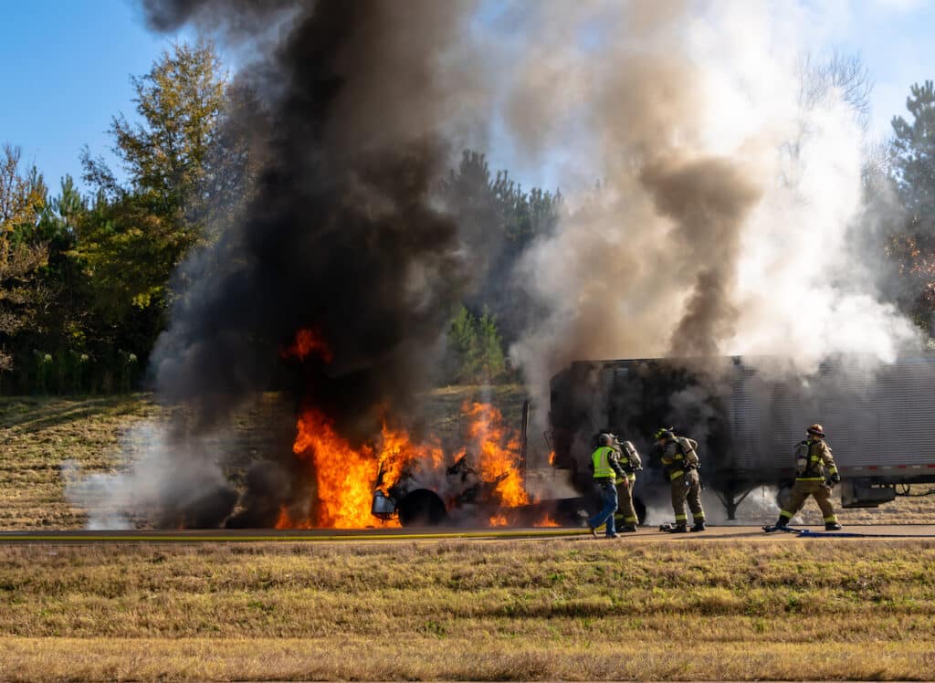 Firefighters extinguishing semi truck flames on highway; traffic blockage; 911 emergency.
